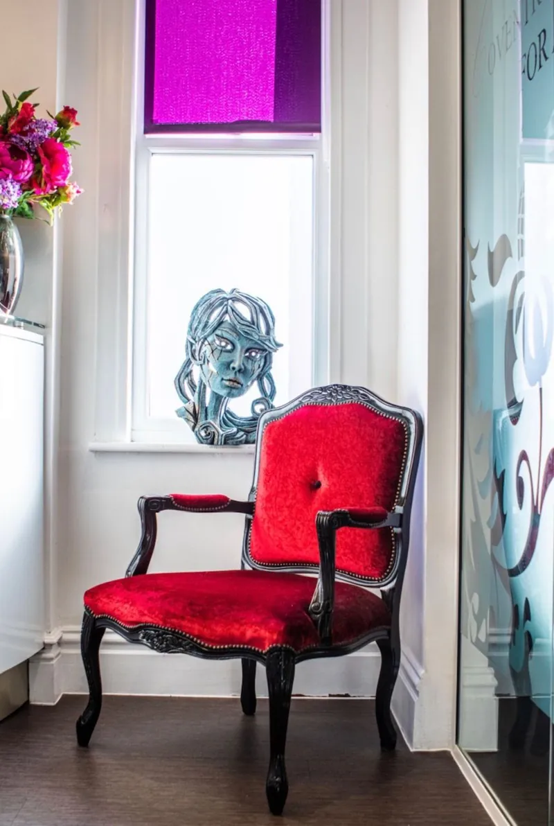 A red velvet chair by the window in the practice